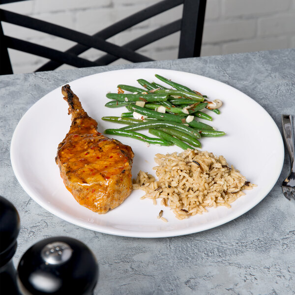 A Libbey white porcelain coupe plate with meat and green beans on it.