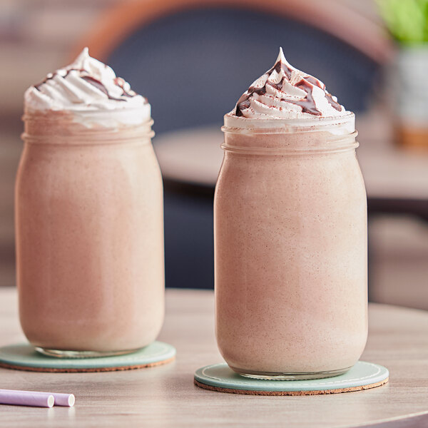 Two glass jars with mocha frappes on a table.