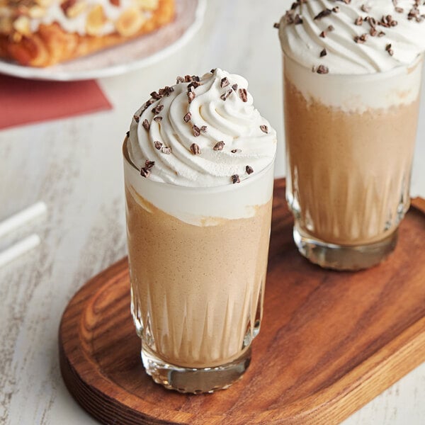 Two glasses of Cappuccine Supreme Classic Latte Frappes with whipped cream and chocolate chips.