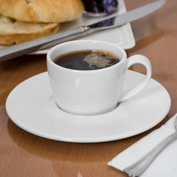 A Libbey Slenda white porcelain saucer with a cup of coffee on it.