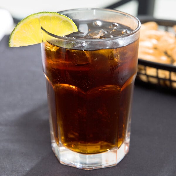 A Libbey Gibraltar beverage glass filled with ice tea with a lemon slice on top.