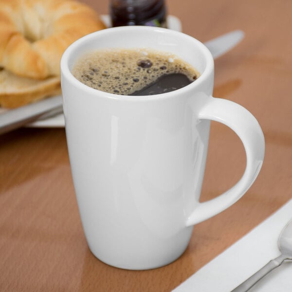 A white porcelain mug filled with coffee on a table.