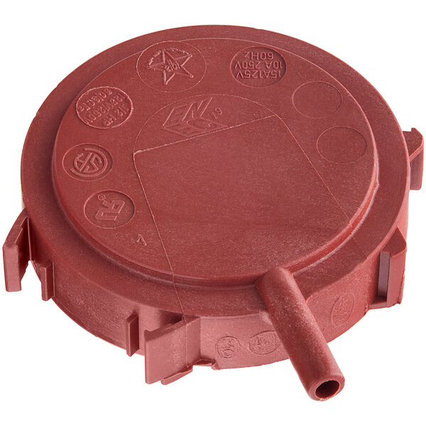 A red plastic pressure switch cover with a circular hole.
