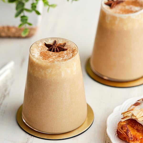 Two glasses of brown Cappuccine Supreme Vanilla Chai Frappe with star anise on top.