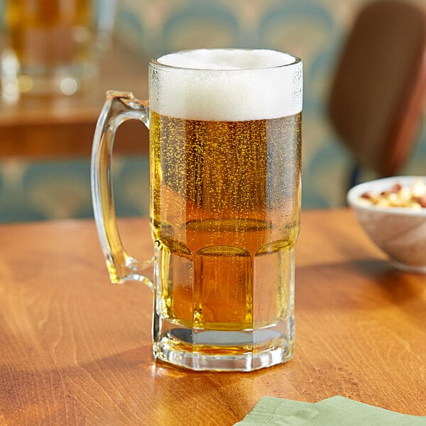 A Libbey Gibraltar beer mug on a table with a glass of beer.