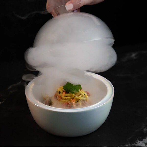 A hand holding a bowl of food with smoke coming out of it using a Flavour Blaster Small Food Cloche.
