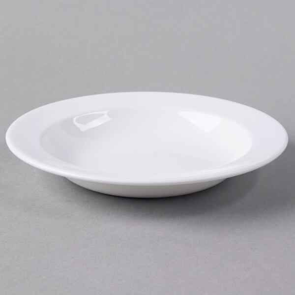 A Libbey white porcelain deep rimmed soup bowl on a gray surface.