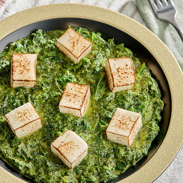 A plate of food with white cubes of Royal Mahout paneer cheese on it.