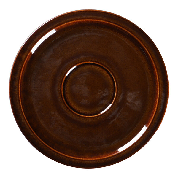 A close-up of a brown RAK Porcelain coffee cup saucer with a circle in the middle.