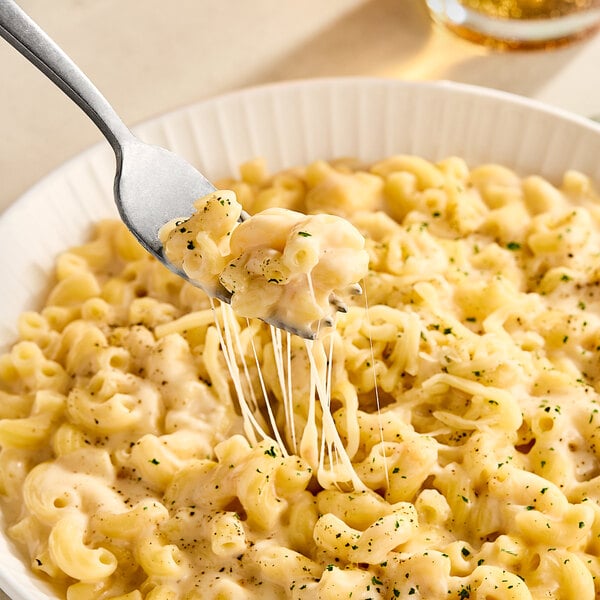 Shredded Ammerlander Smoked Gouda cheese on a fork over a bowl of macaroni and cheese.