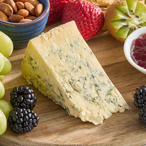 A wooden board with Coombe Castle Blue Stilton cheese, strawberries, and kiwi.