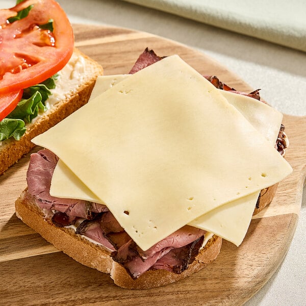 Sliced Gouda cheese on a sandwich on a wooden board.