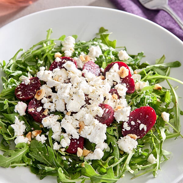 A white plate with a salad of beets and goat cheese.