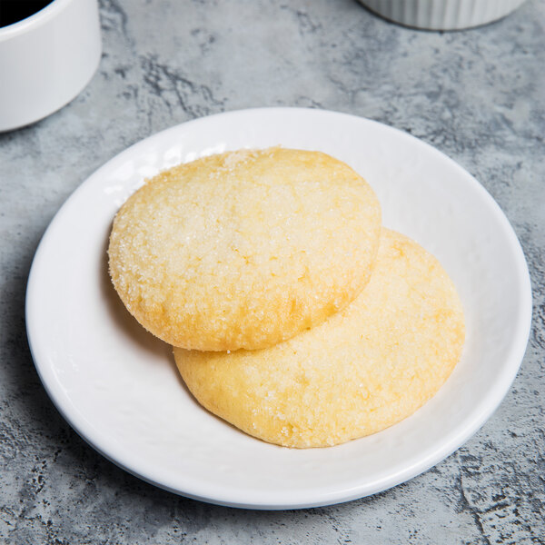 A white Elite Global Solutions round plate with two cookies on it.