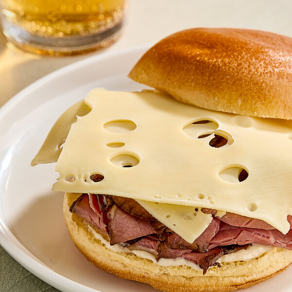 A sandwich with Ammerlander Swiss cheese and meat on a plate.