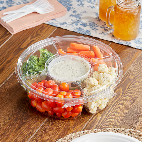 A clear Inline Plastics plastic tray with 5 compartments filled with tomatoes, broccoli, carrots, and white sauce.