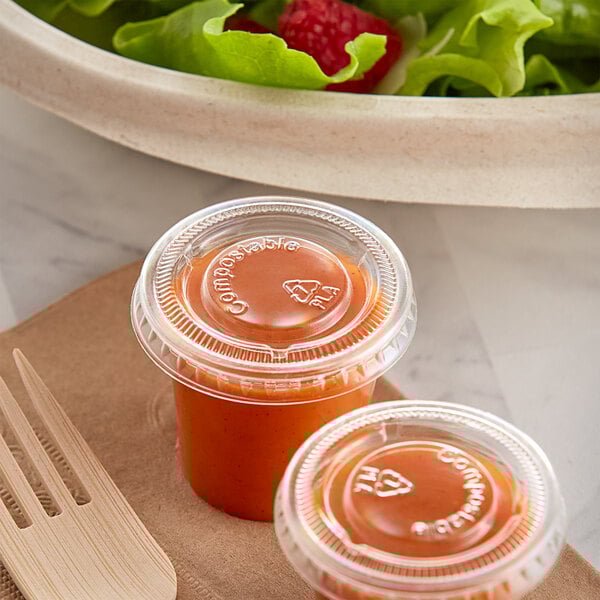 The World Centric compostable portion cup lid on two small containers of tomato sauce.