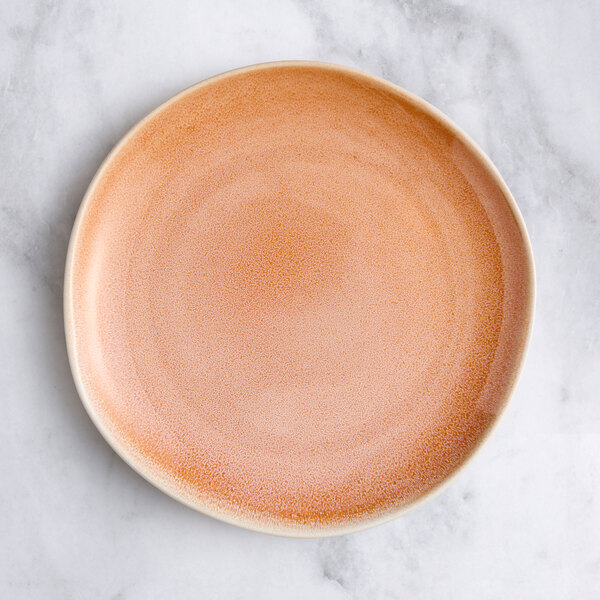 An Acopa Highlands primrose pink coupe china plate on a marble surface.