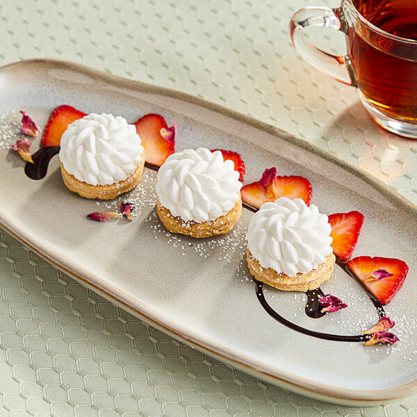 A white swirly Pavoni Pavoflex Facon pastry on a plate with strawberries and chocolate.