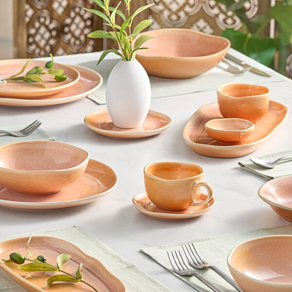 A table set with white dishes and peach mugs.