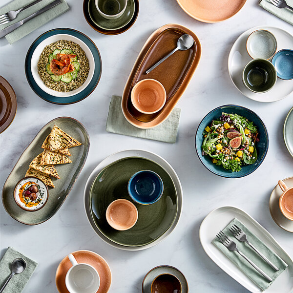 A collection of assorted ceramic plates, bowls, and cups in various colors and sizes arranged on a white surface.
