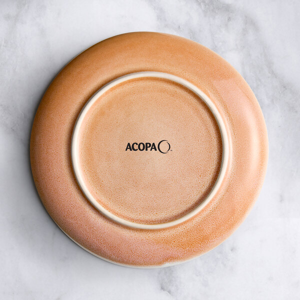 An Acopa Highlands primrose pink coupe plate on a marble surface.