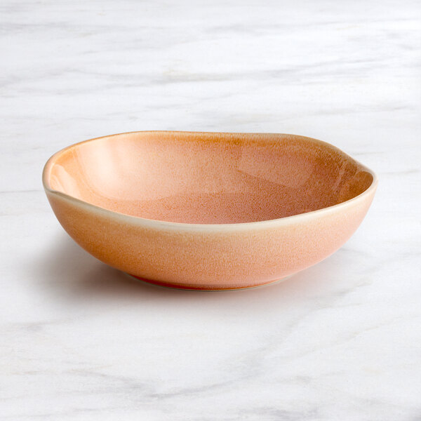 A round Acopa Primrose pink china bowl on a marble surface.
