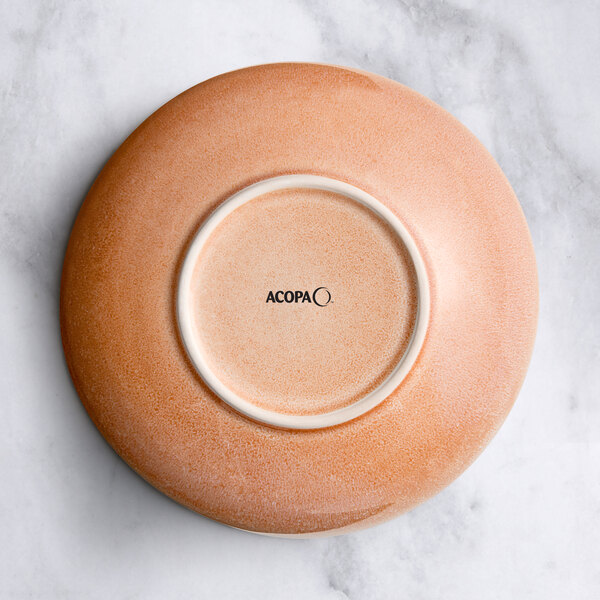 A round primrose pink ceramic bowl on a marble surface.