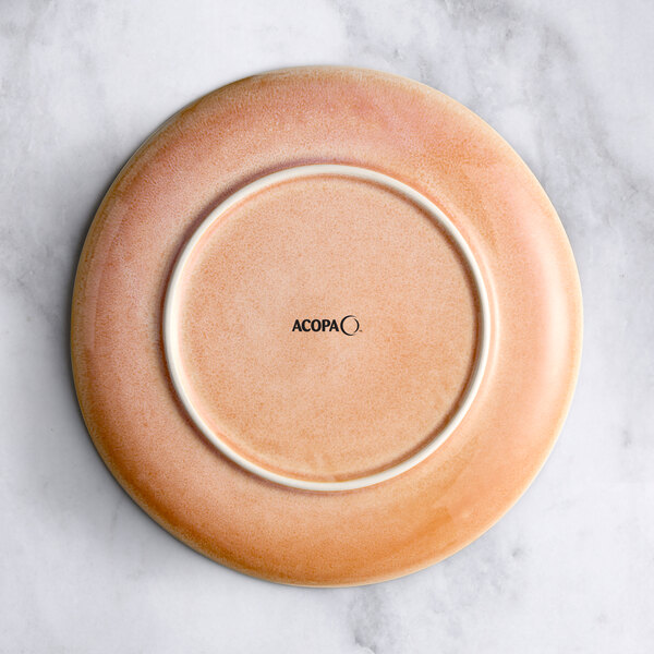 An Acopa Highlands Primrose Pink coupe china plate on a marble surface.
