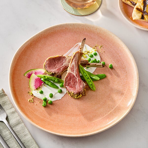 An Acopa Highlands Primrose Peach coupe china plate with meat and vegetables on it.