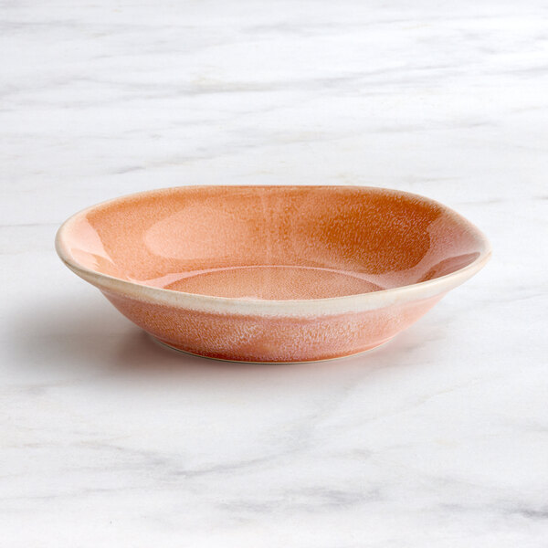 An orange Acopa Highlands china bowl on a marble surface.