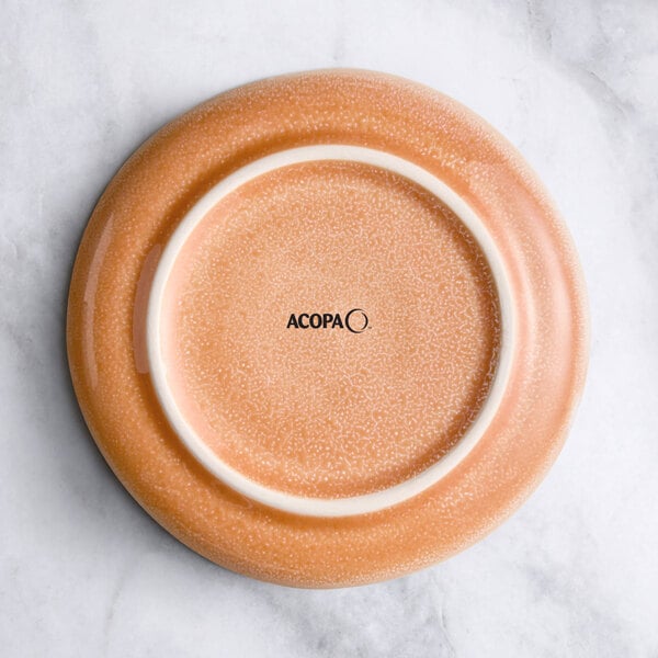 A round pink ceramic saucer on a marble surface.