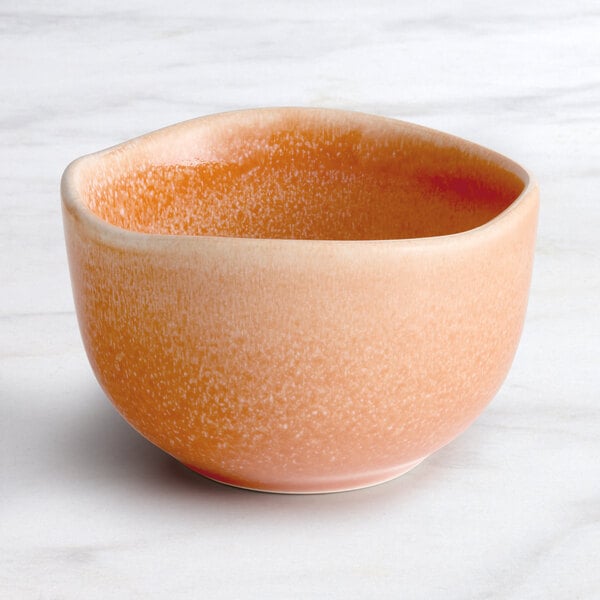 An Acopa Primrose Pink bouillon cup with a small amount of orange soup in it.