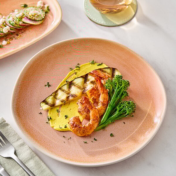 An Acopa Highlands Primrose Peach china plate with shrimp and broccoli on a table.