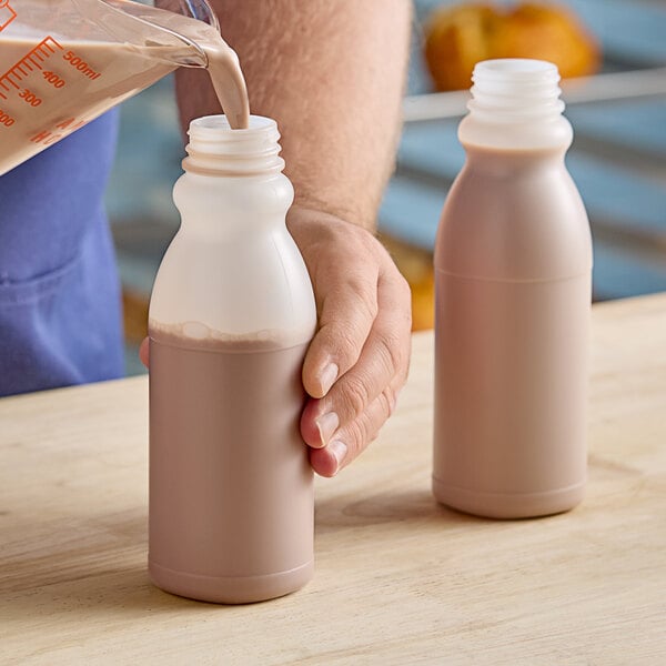 A person pouring milk into a white bottle.