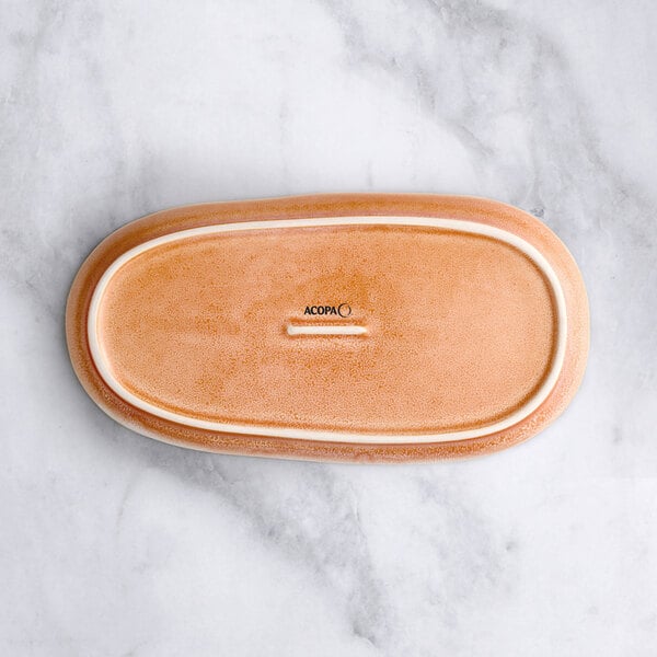 An Acopa Primrose peach coupe china tray with brown bread on a marble surface.