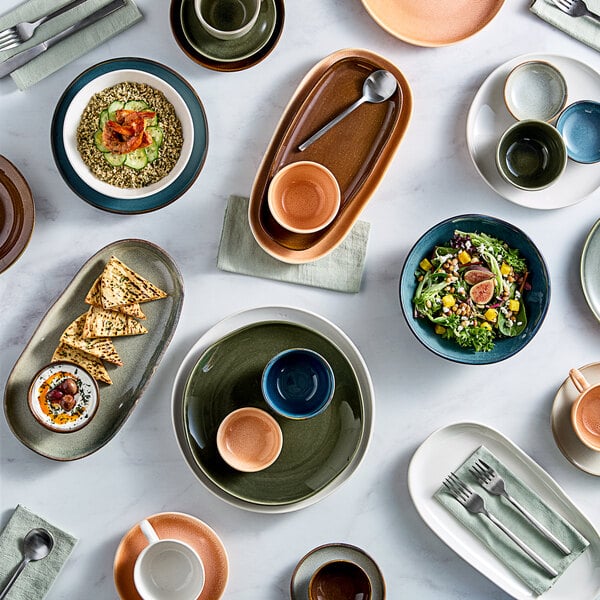 An Acopa Primrose Peach coupe tray on a table with plates and bowls of food.