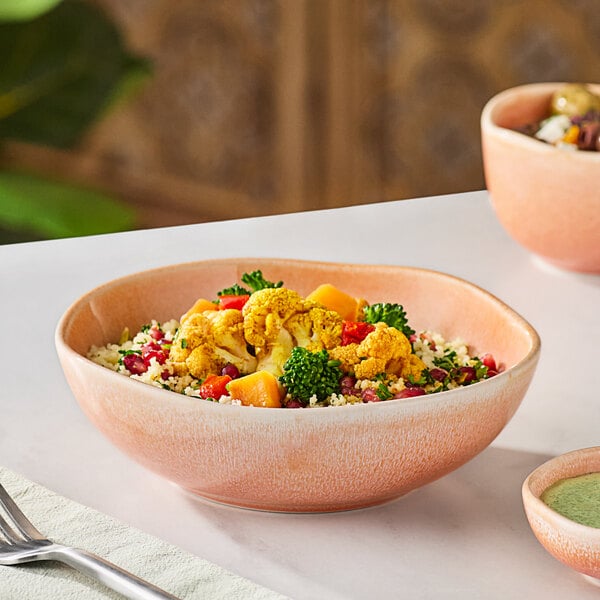 A bowl of food sits on a table next to a bowl of soup.