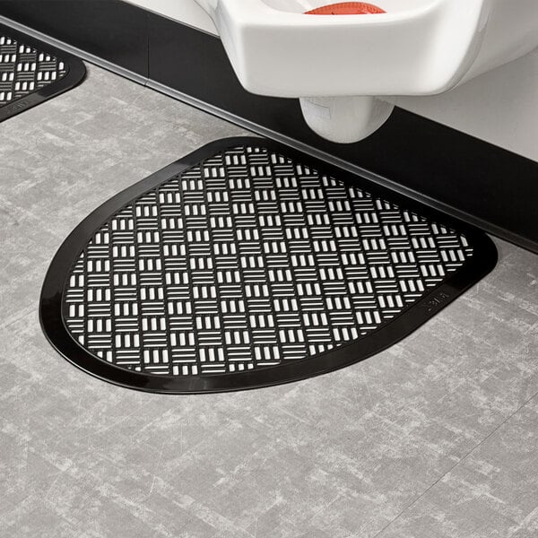 A black Lavex Disposable urinal floor mat on a bathroom floor.