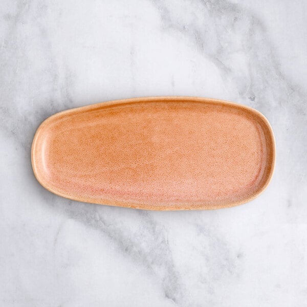 An Acopa Primrose Peach coupe tray with an oval shape and brown rim.