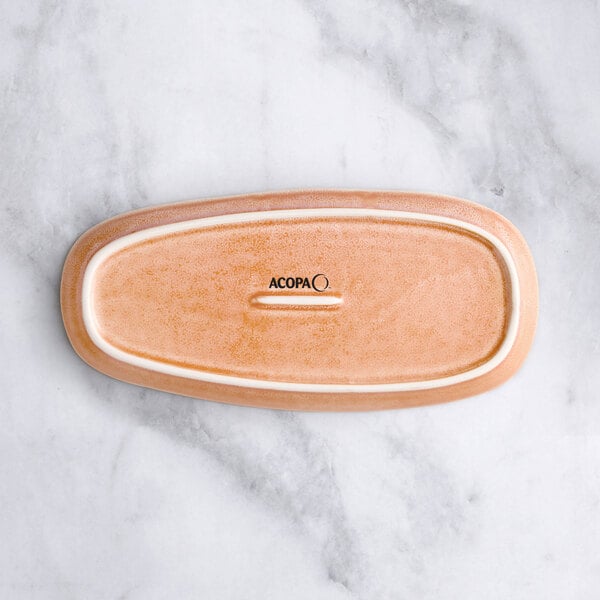 An Acopa Primrose peach coupe tray with an oval shape and rectangular design.
