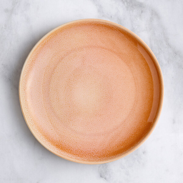 An Acopa Highlands primrose pink coupe china plate on a marble surface.