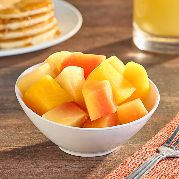 A bowl of Port Royal tropical fruit salad on a table with a fork.