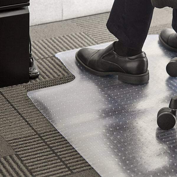 A person sitting in a black office chair on a clear lipped office chair mat.