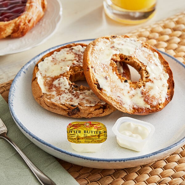 A plate of bagels with Sommer Maid whipped butter and a jar of jam on a table.