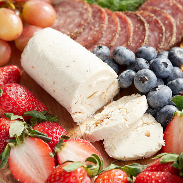 A wooden cutting board with Vermont Creamery Strawberry Spritz goat cheese, fruit, and berries.