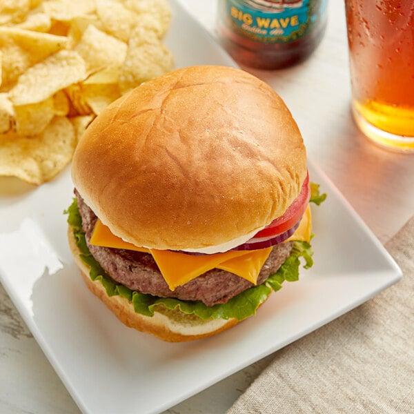 A cheeseburger with lettuce and tomato on a King's Hawaiian sandwich roll with a side of chips.