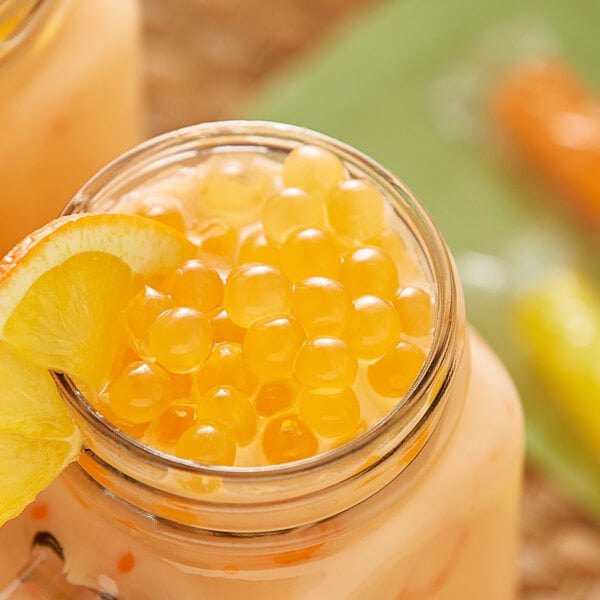 A glass jar of Bossen Sour Orange Bursting Boba in orange liquid with orange slices.