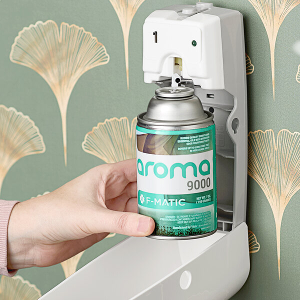 A hand using an F-Matic Fresh Linen scented air freshener spray.