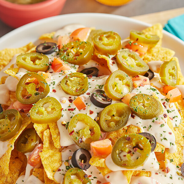 A bowl of nachos with jalapenos and cheese.